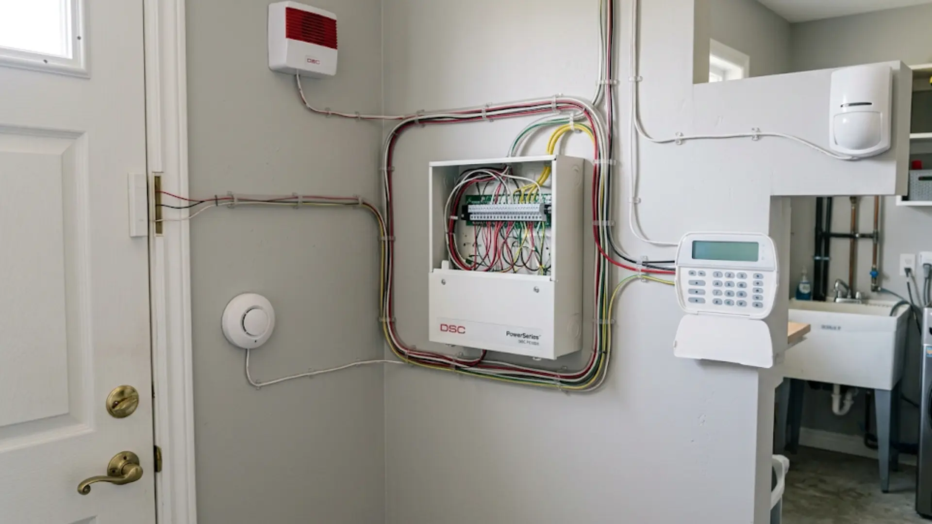 Low-voltage cables connect door sensors, motion detectors, keypads, and sirens to a central alarm control panel