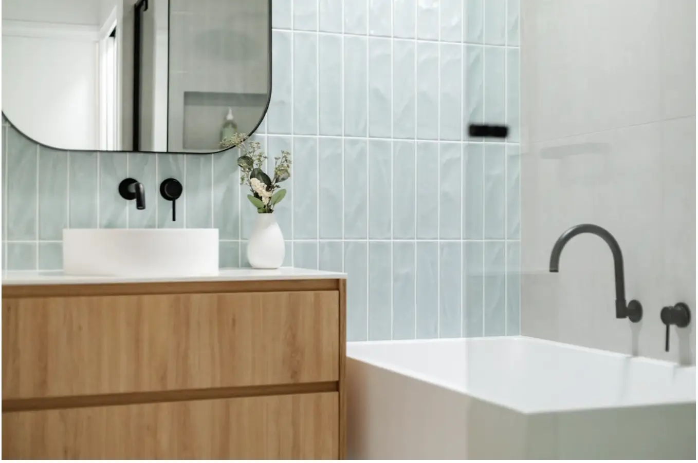 Modern bathroom with wooden vanity, ceramic basin, and light blue tiled wall