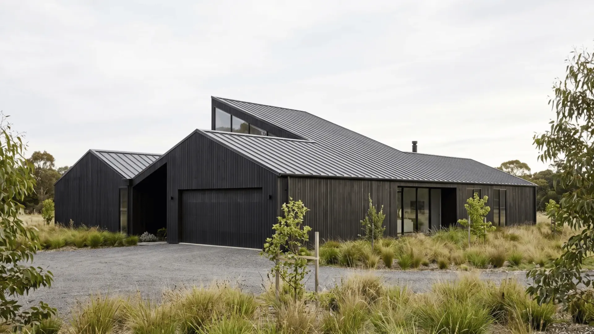 Black modern home with angled roof planes, dark cladding, and a clearly visible sloped roof profile