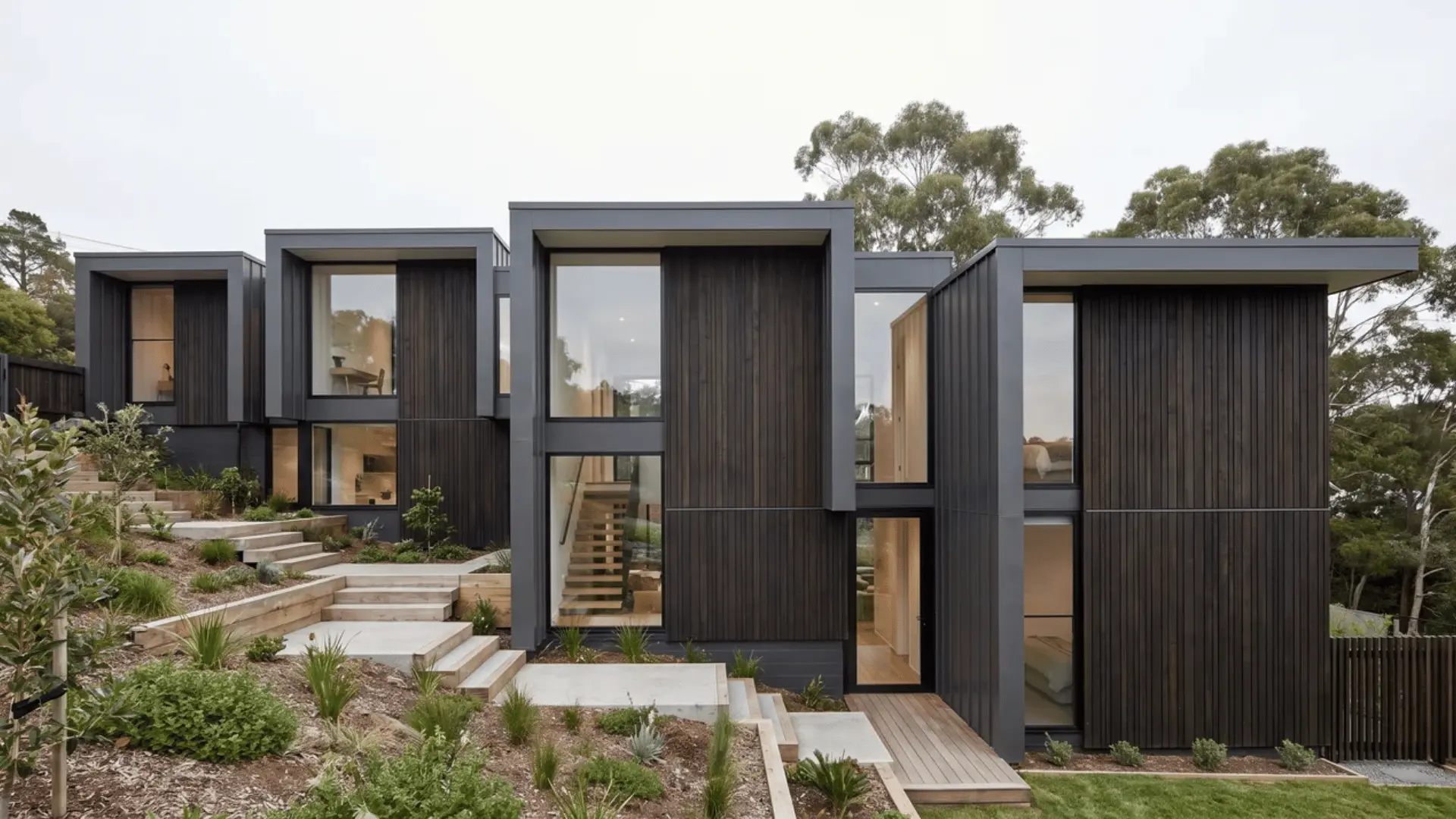 Black split-level house on a slope with staggered floors, offset rooflines, and windows at changing heights