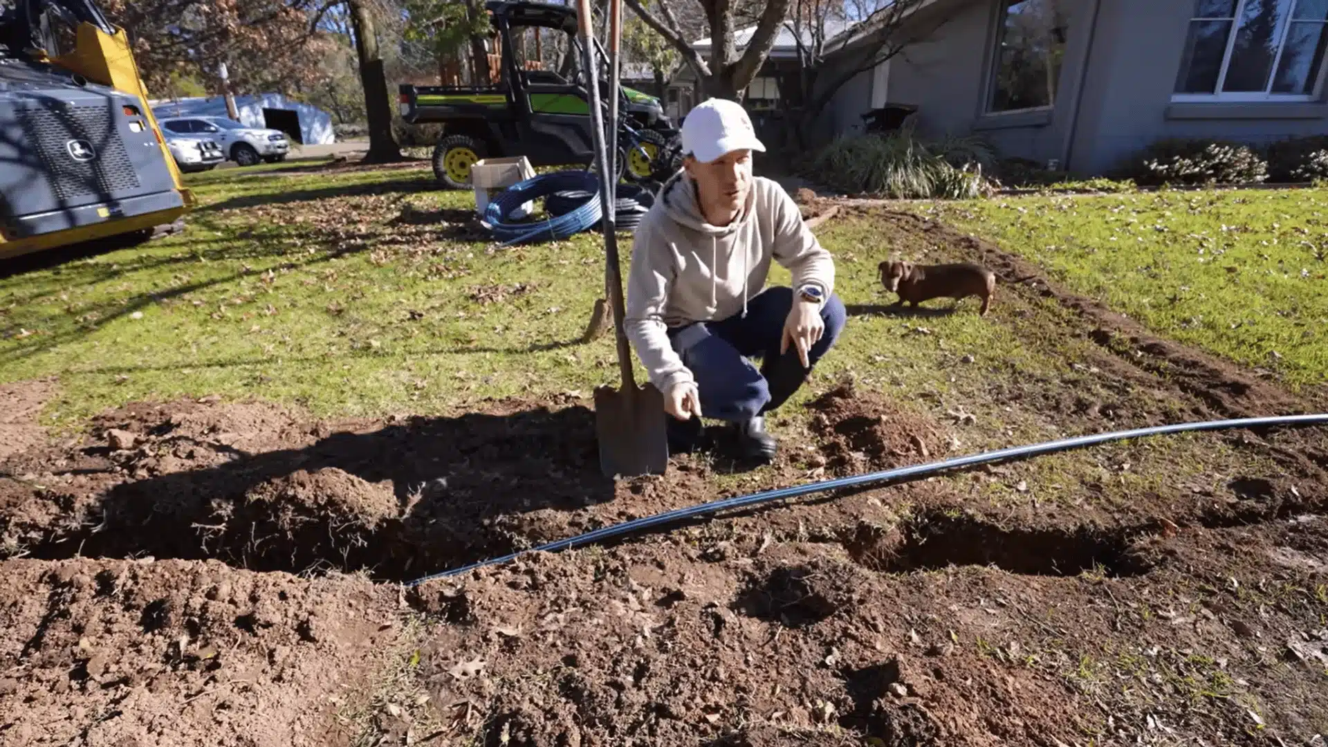 Blue irrigation pipe laid beside open lawn trenches during sprinkler system installation.