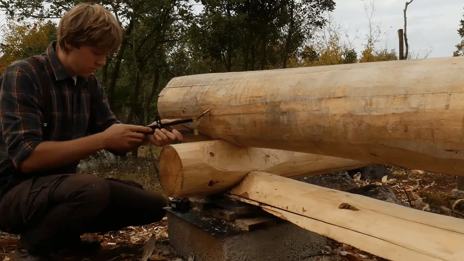 Using a log scriber to mark the shape of the lower log onto the upper wall log for a close fit