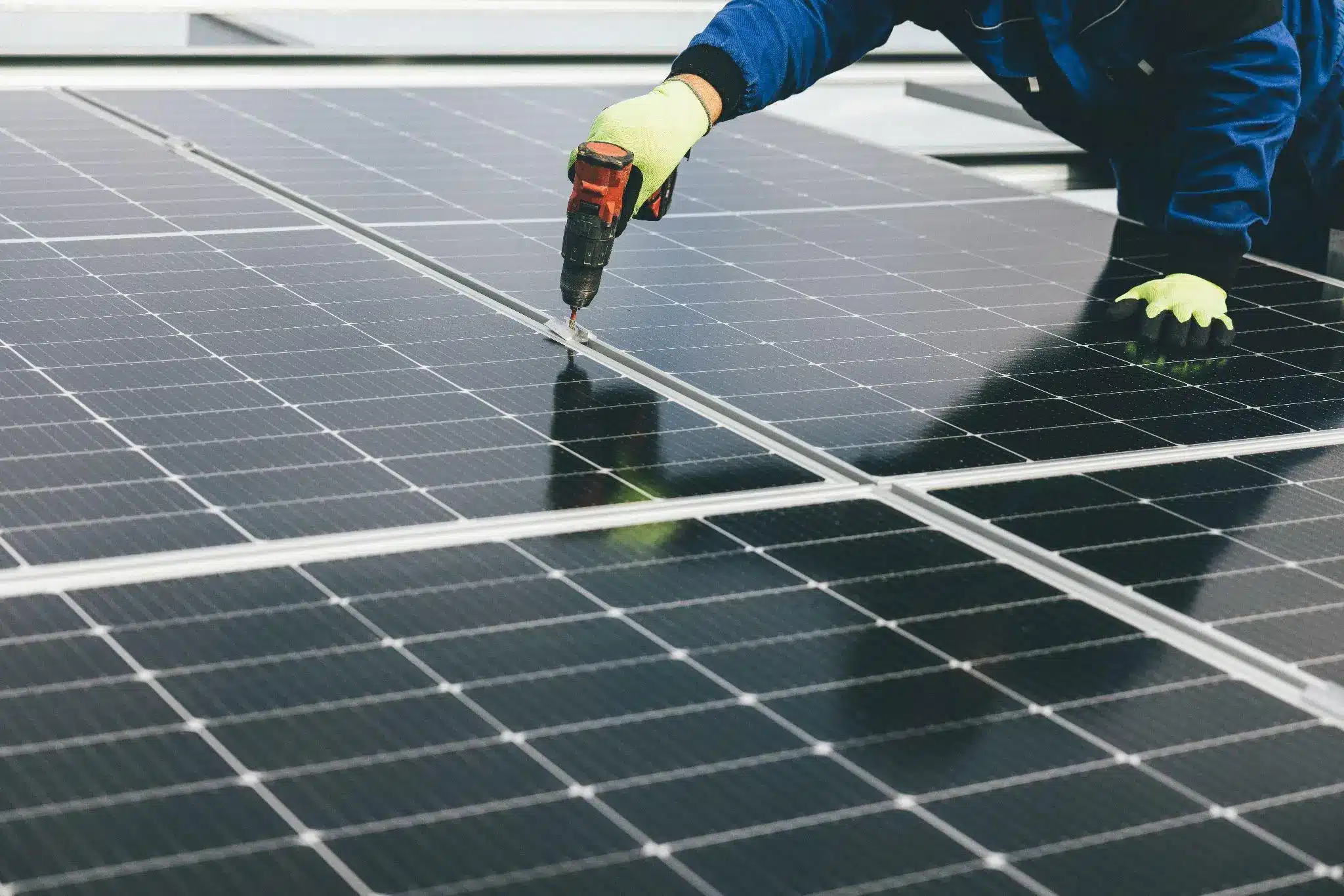 Technician using drill on rooftop solar panel installation outdoors