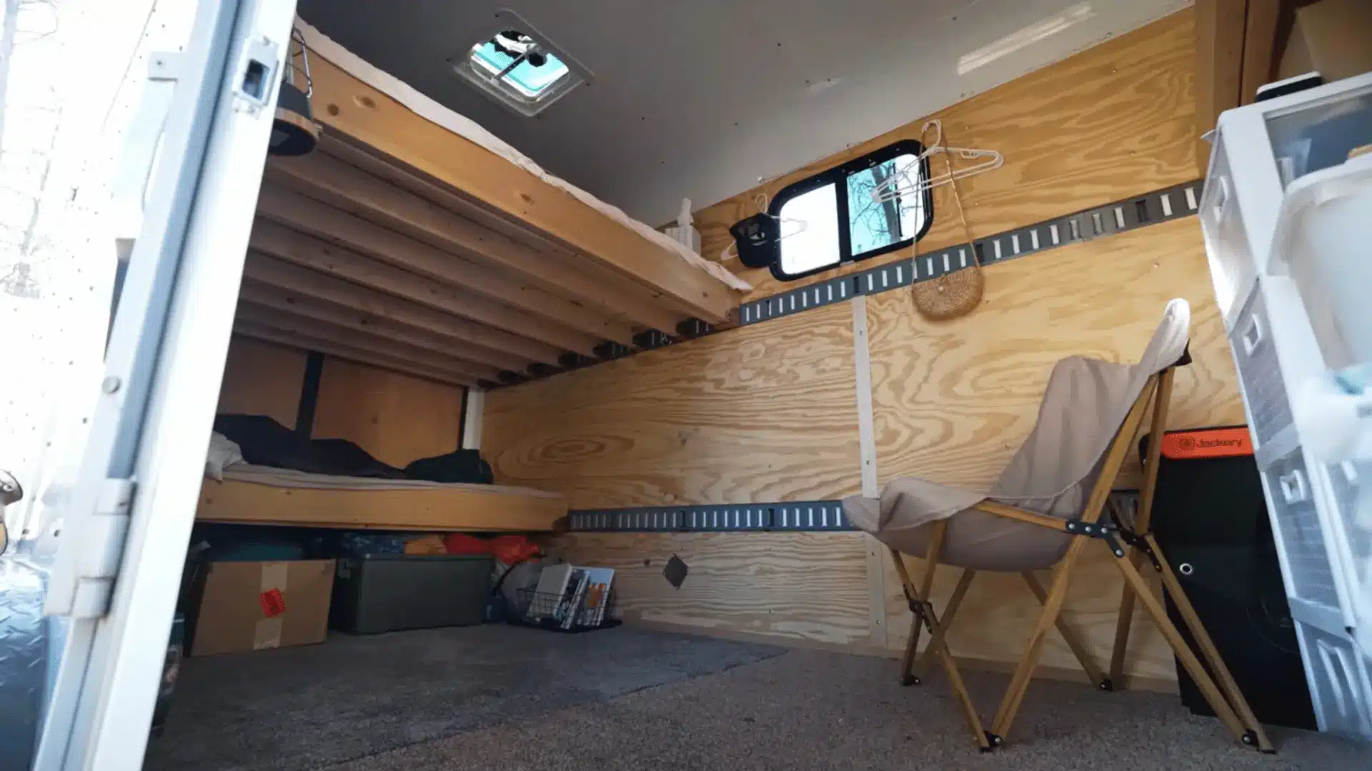 Cargo trailer interior showing raised bed platforms with sleeping areas and storage space underneath.