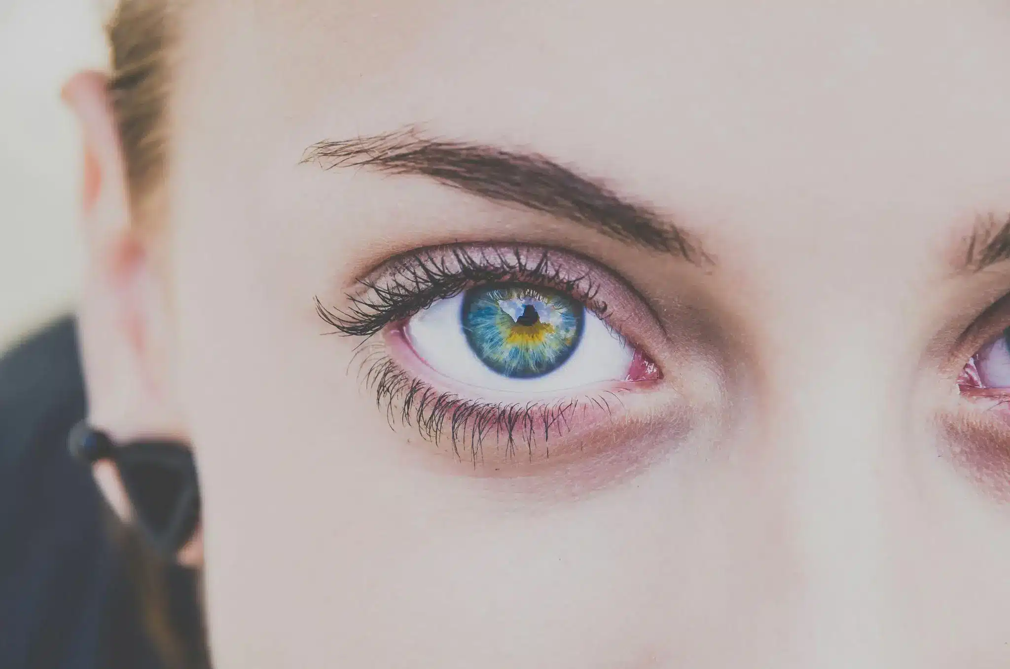Close-up of a person's blue-green eye with long eyelashes and natural lighting