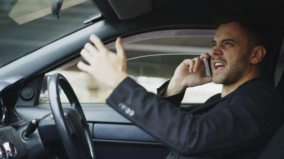 Man in car making a phone call with frustrated expression
