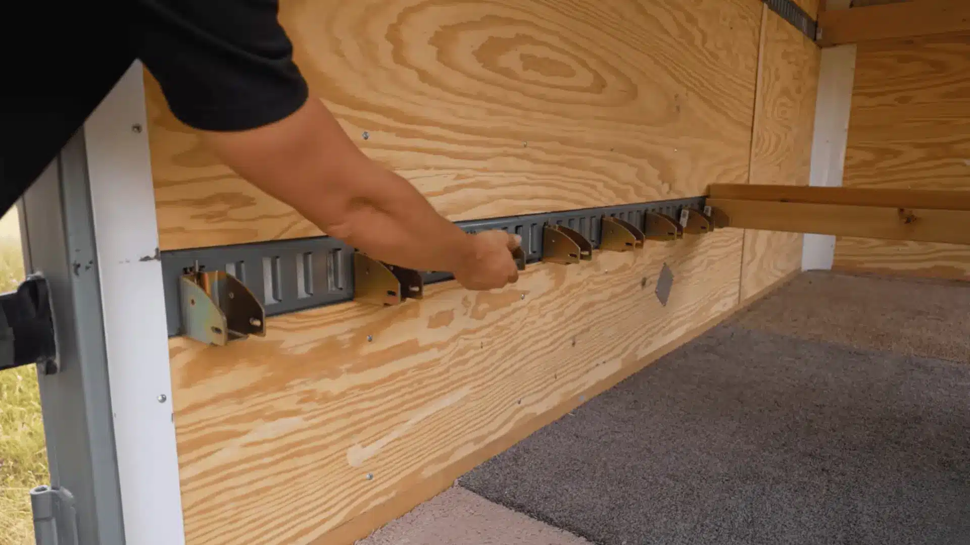 E-track rail system installed inside cargo trailer with support brackets attached along the wall.