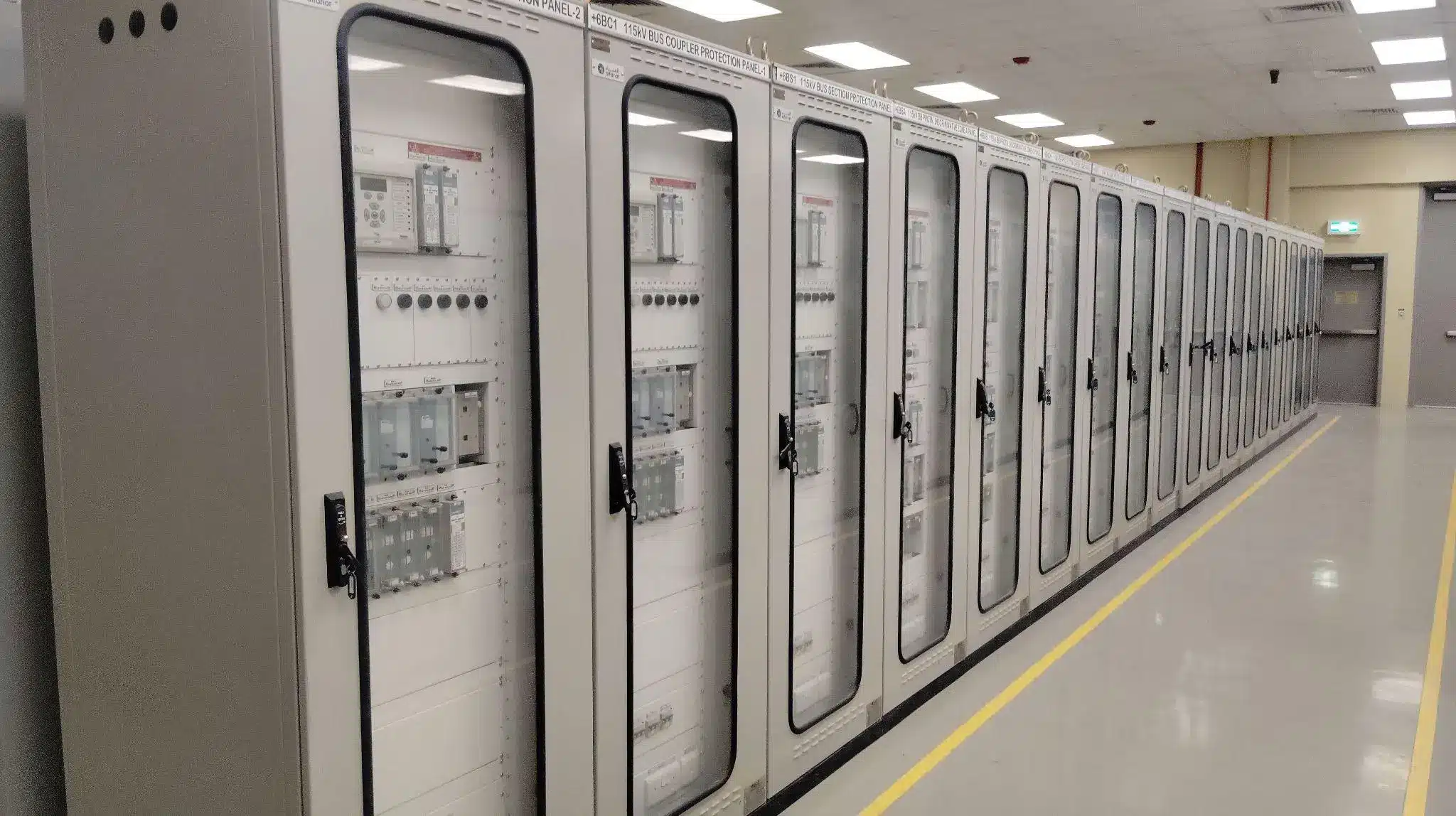 Row of control panels with glass doors in a brightly lit industrial room