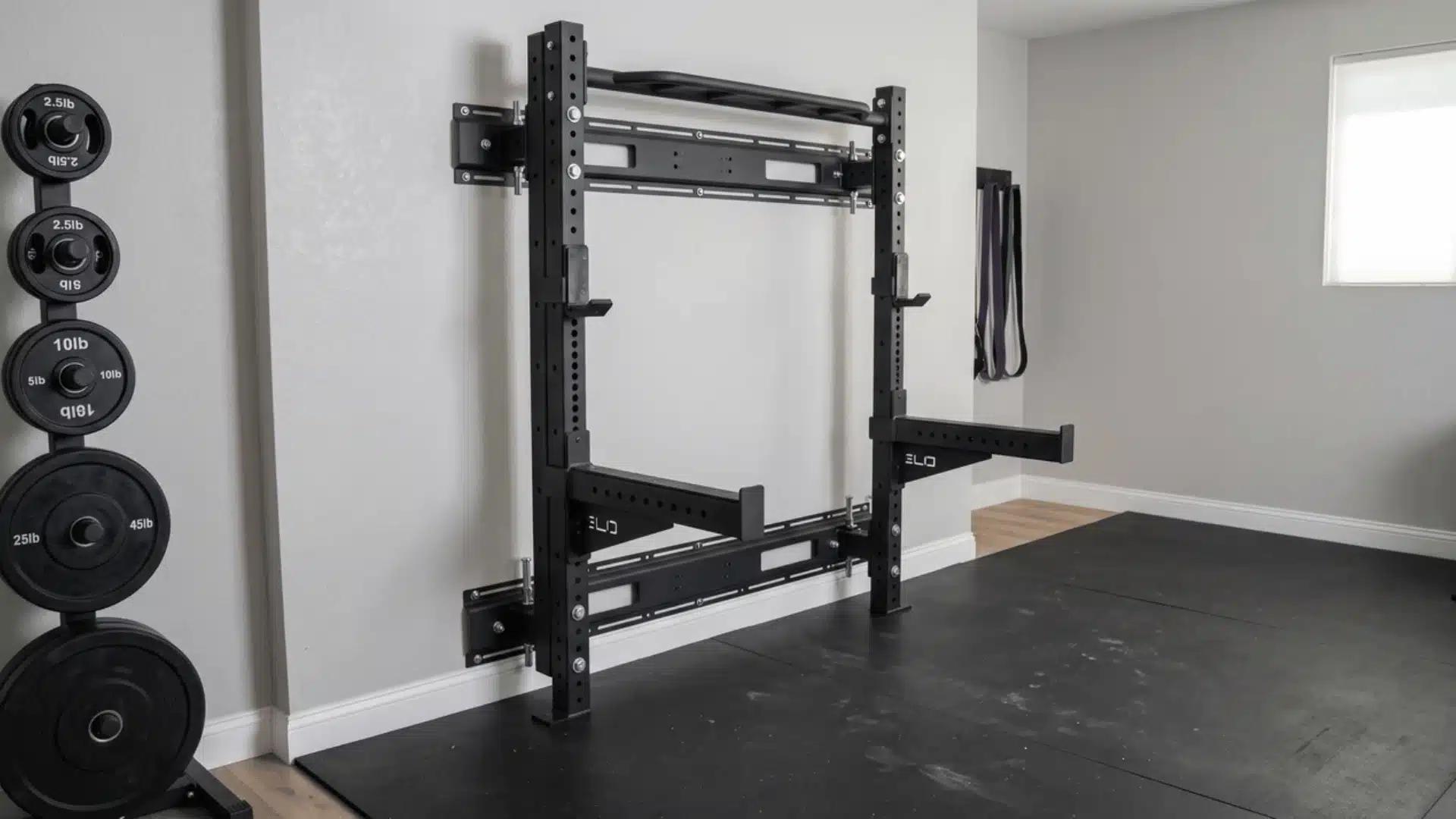 Folding wall-mounted squat rack folded flat against a home gym wall