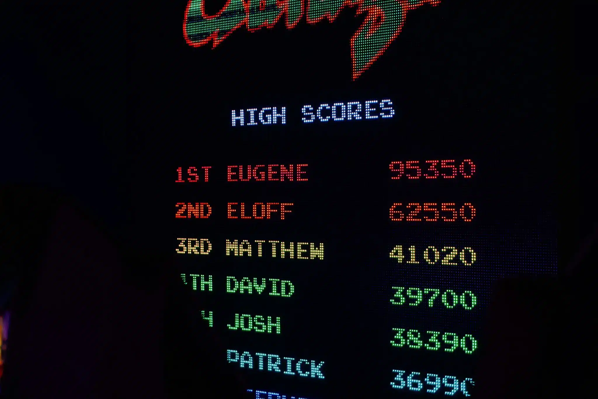 Arcade game high score leaderboard with colorful text in dimly lit setting
