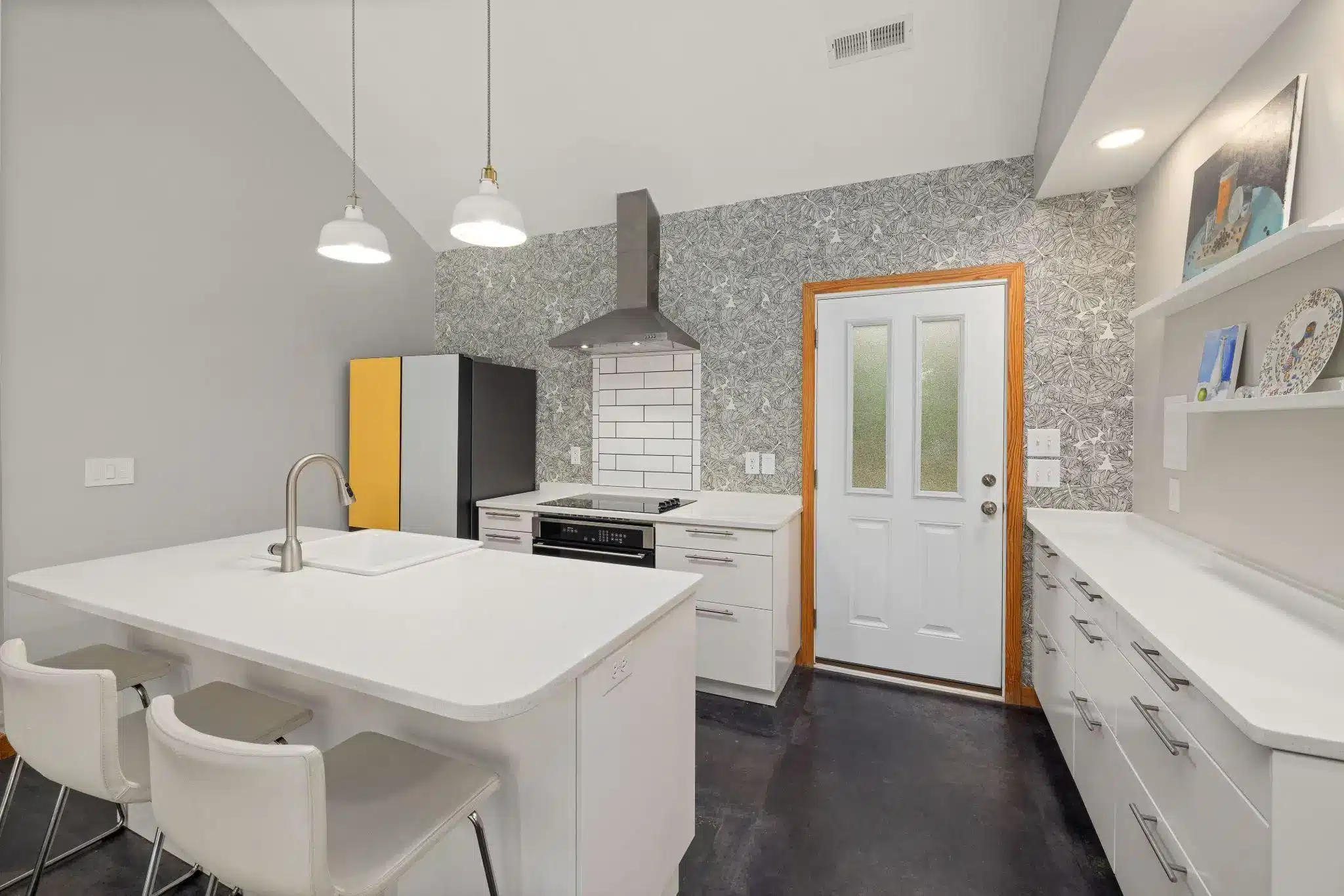 Modern kitchen with white cabinets, island with sink, and colorful refrigerator panels
