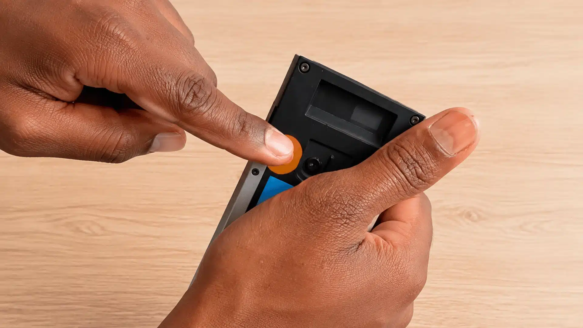 Hand pressing the orange setup button on a Ring doorbell to start Wi-Fi reconnection mode.
