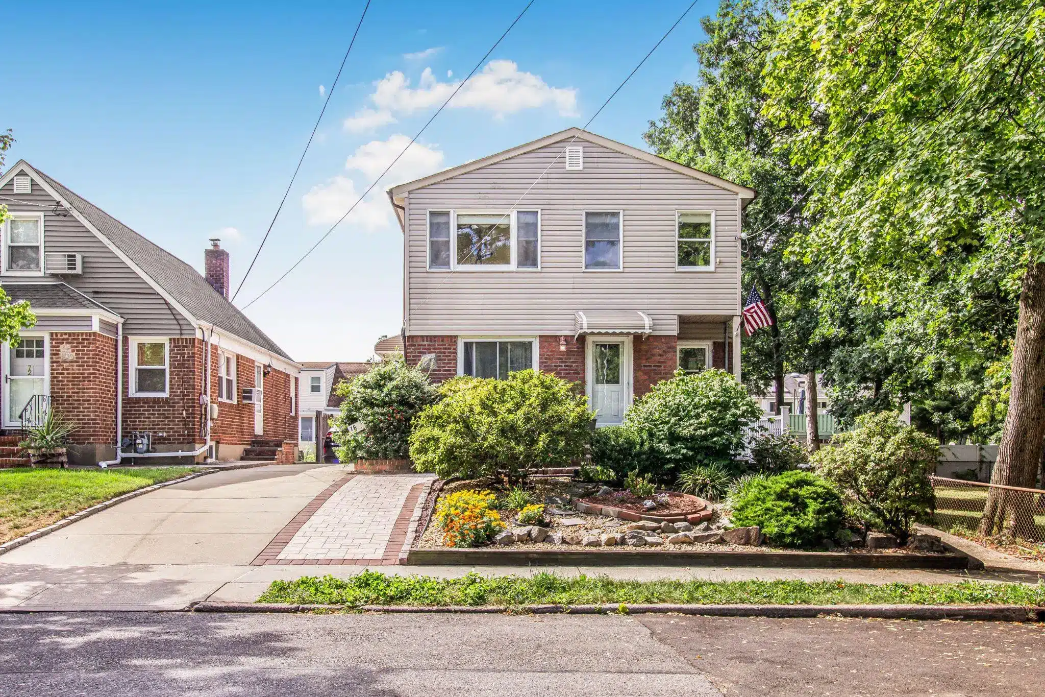 Two-story suburban house with brick facade and front garden under clear blue sky