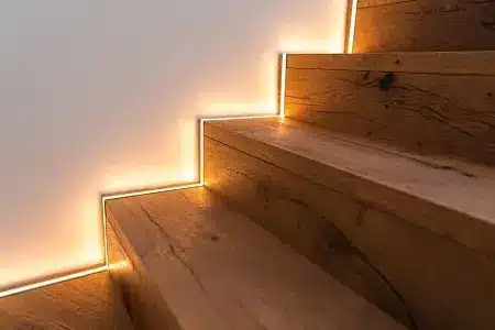 Wooden staircase with integrated warm LED lighting along edges in modern interior setting