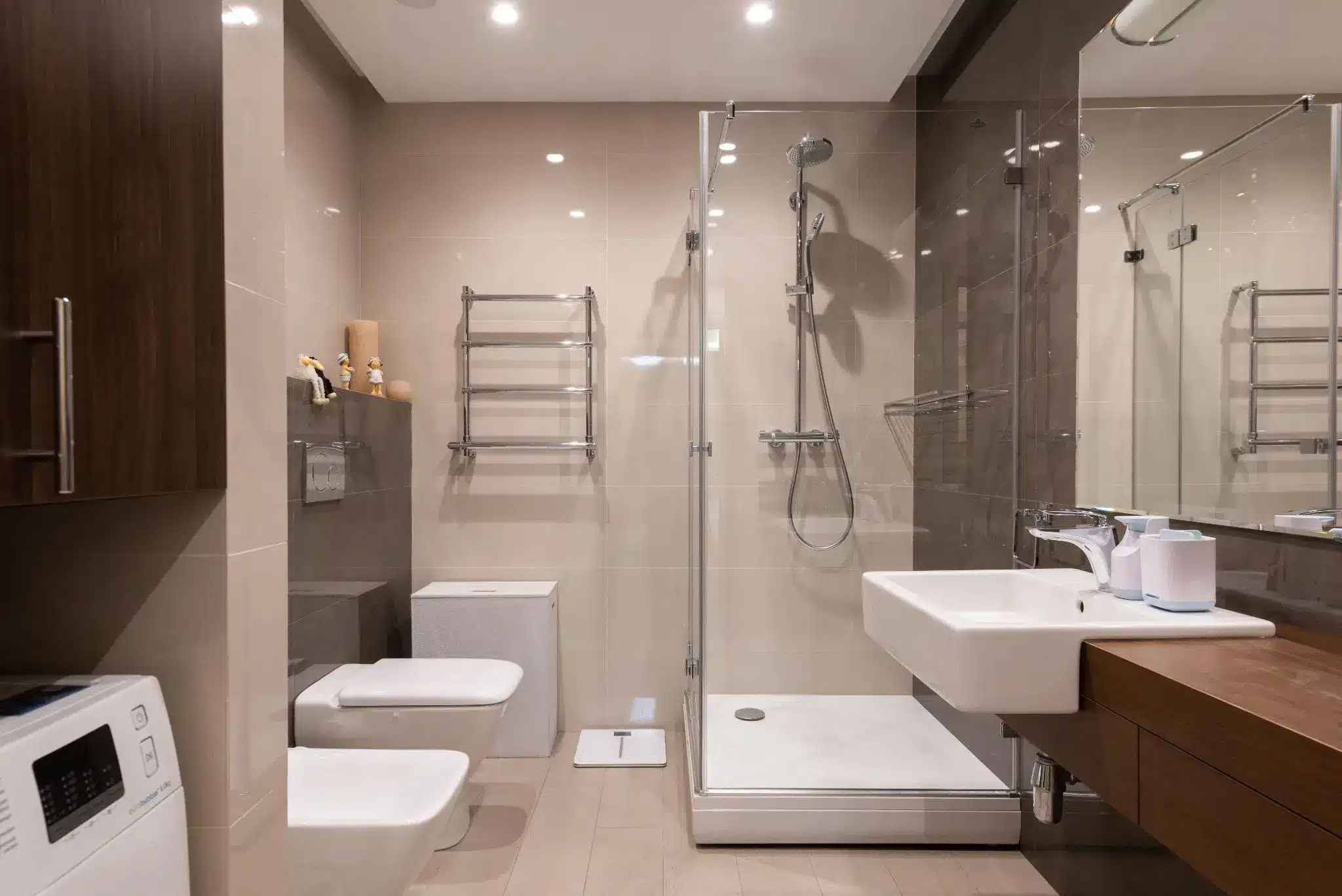 Modern bathroom interior with glass shower, white fixtures, and wooden vanity in neutral tones