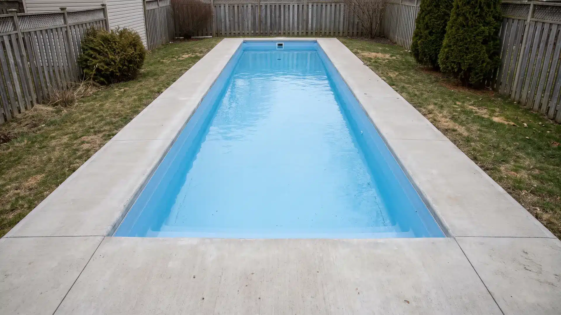 Narrow 30 to 35 foot rectangular lap pool with vinyl liner and poured concrete decking