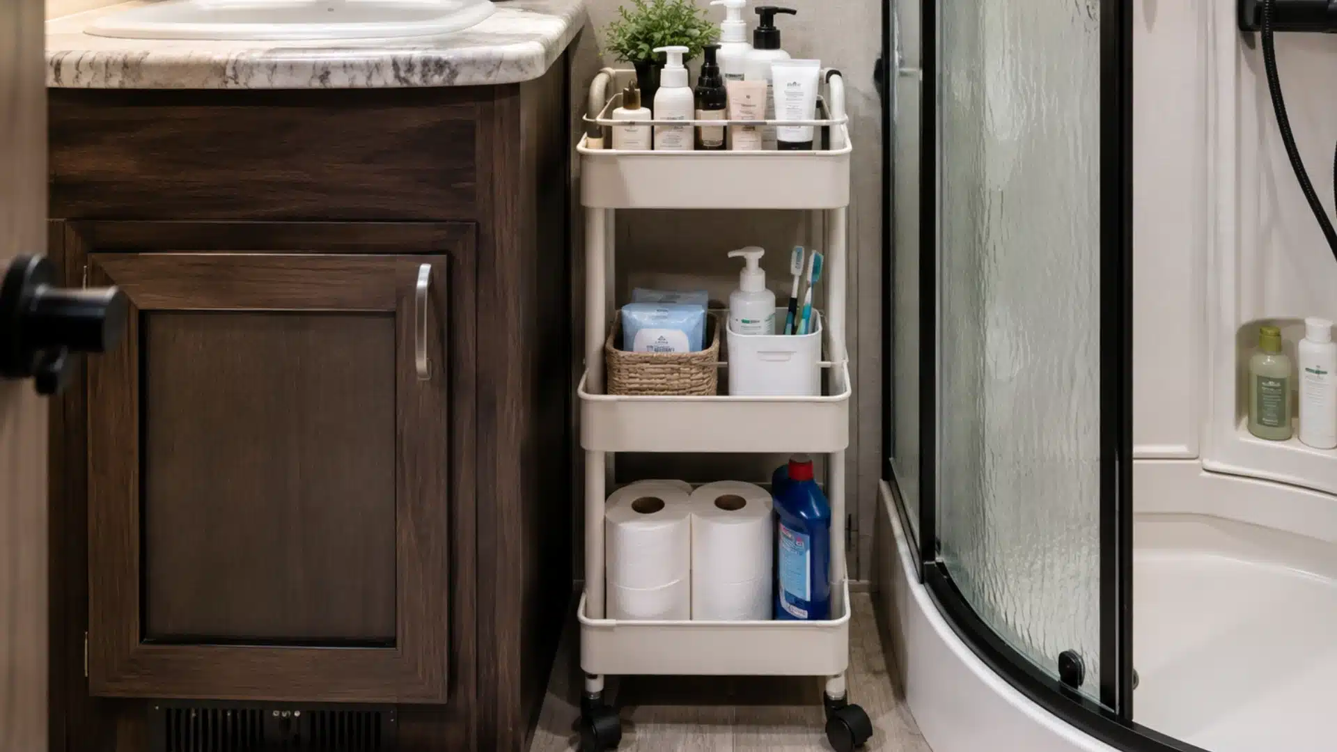 Narrow rolling cart stores toiletries and toilet paper beside an RV bathroom vanity