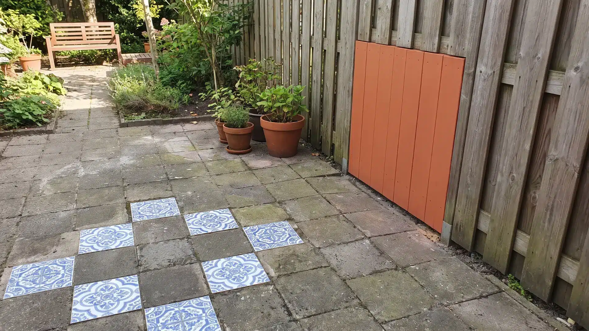 Patterned tiles set into plain pavers beside a painted patio accent panel