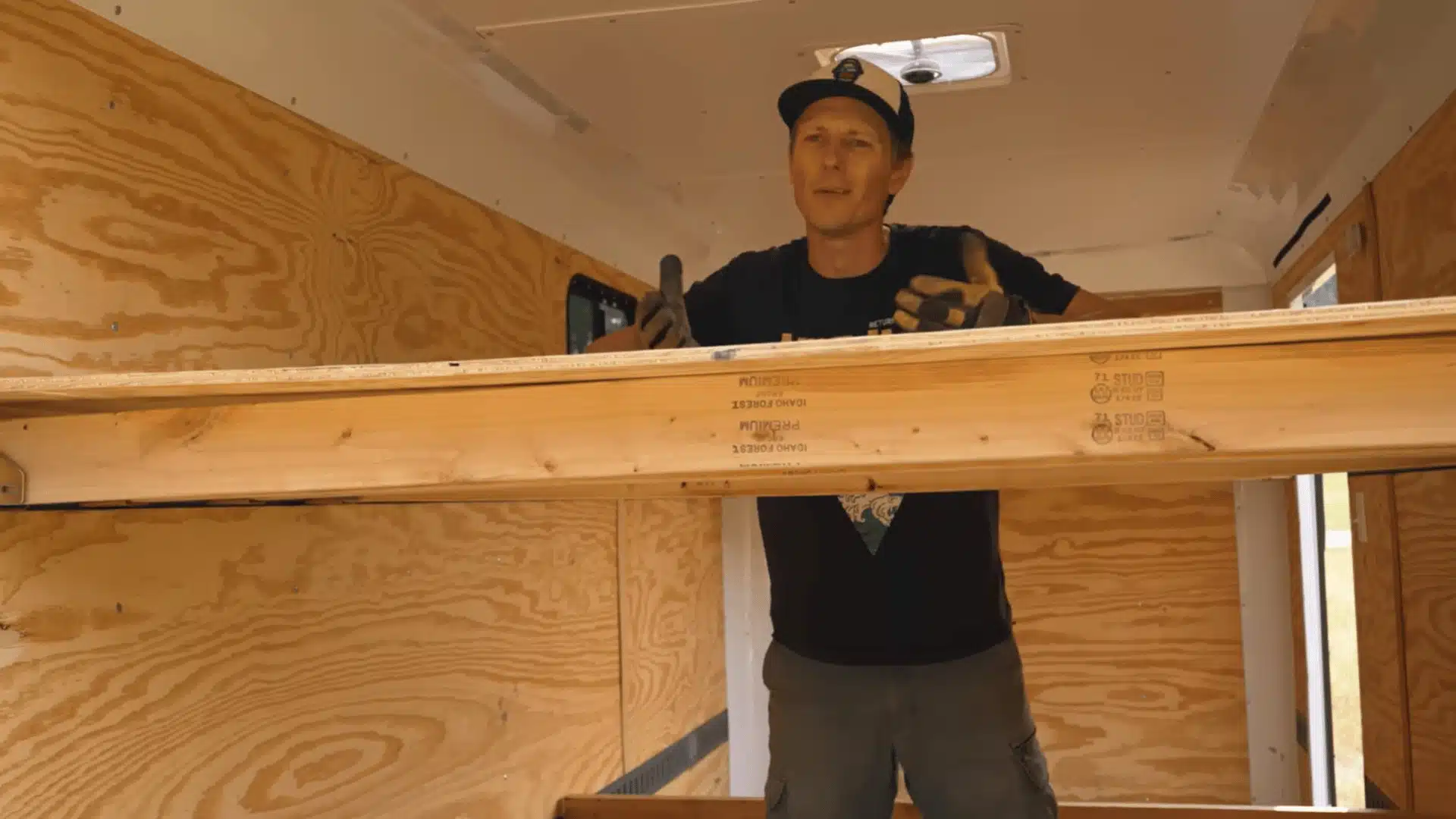 Plywood sheet being positioned over 2x4 supports to create a cargo trailer bed platform.