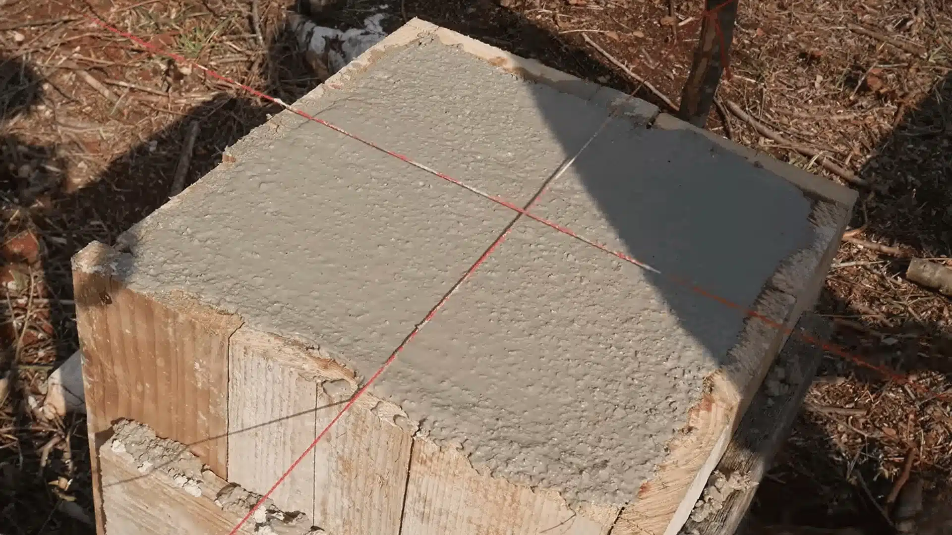 Fresh concrete foundation pad aligned with string lines marking the cabin's measured footprint