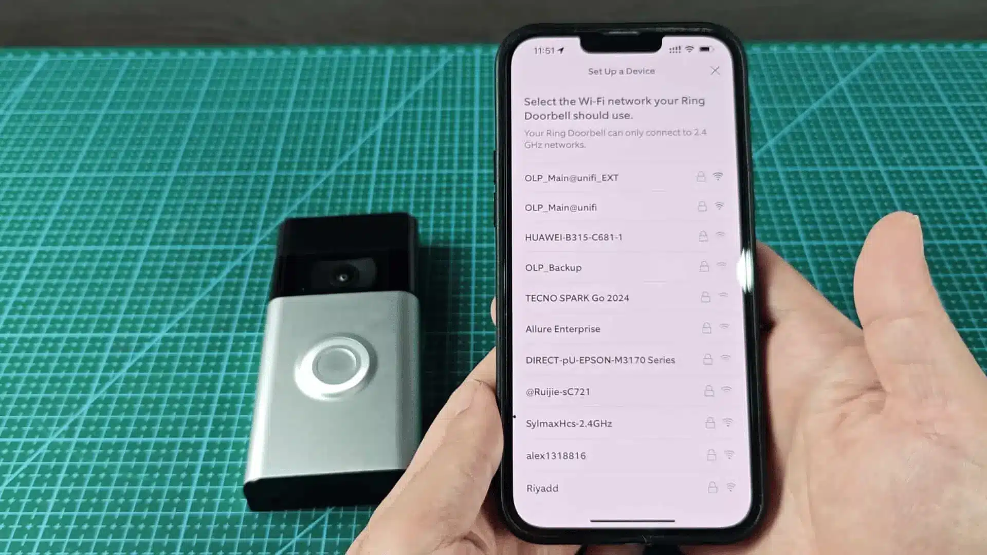 Ring doorbell beside a phone showing available Wi-Fi networks during setup