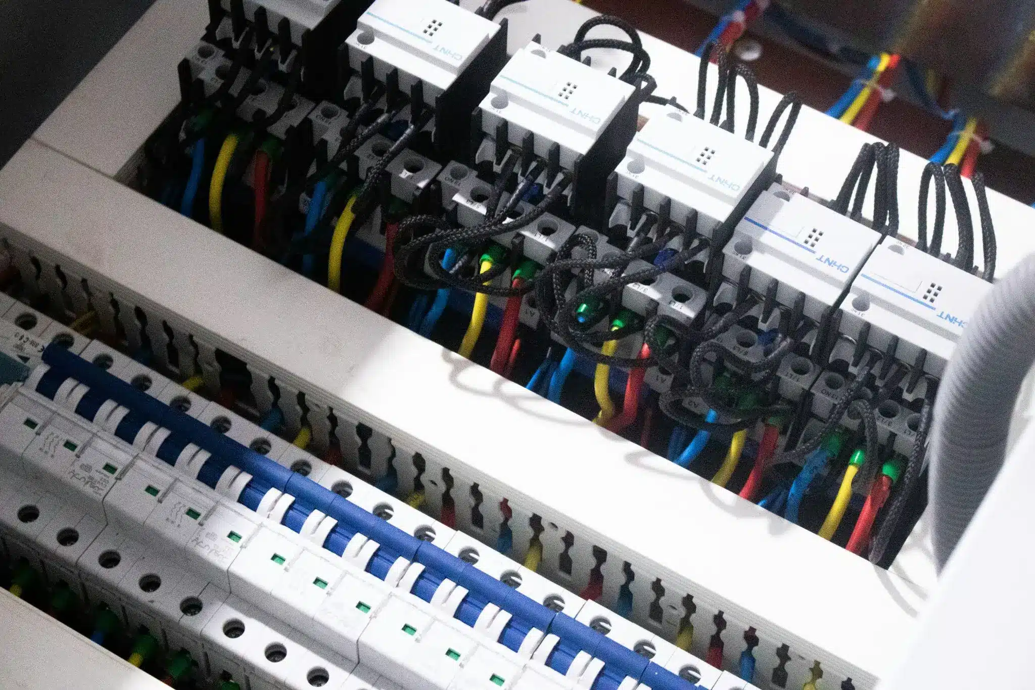 Electrical panel with colorful wires and circuit breakers in a well-lit control room
