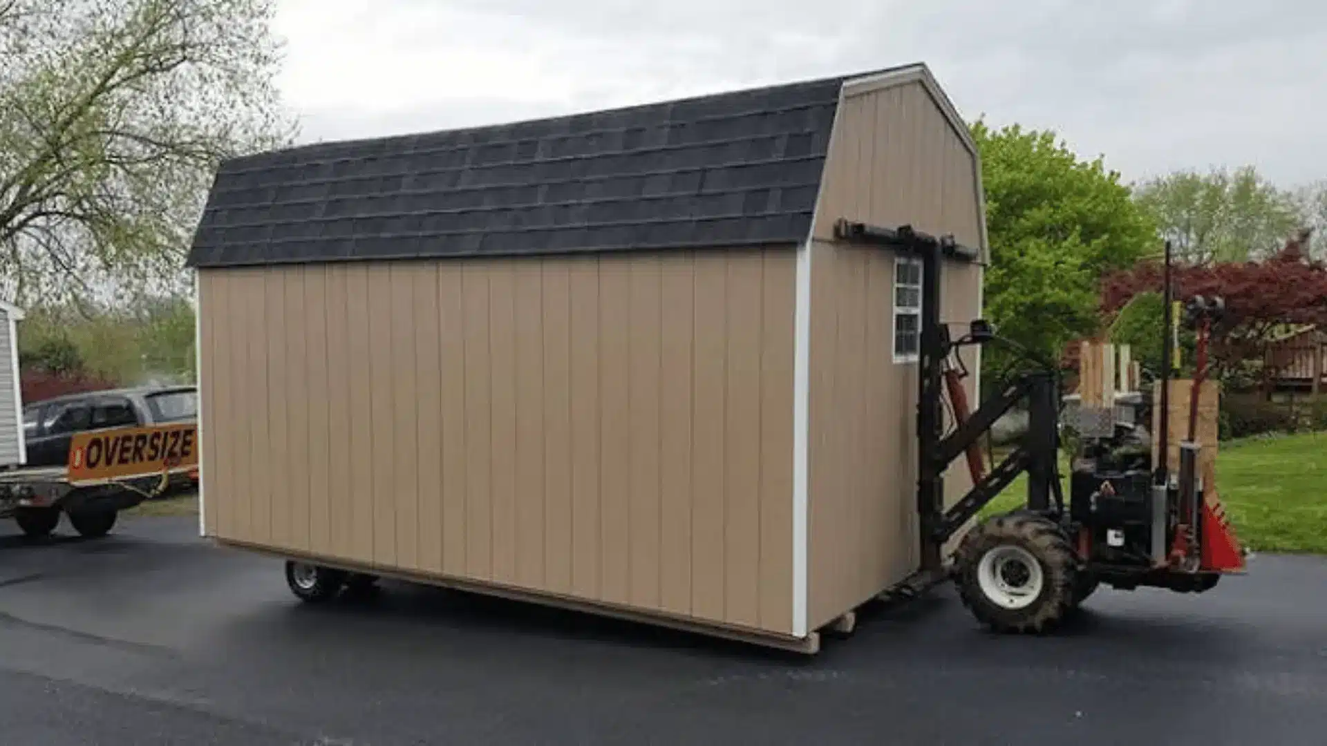 Shed being moved with a forklift attachment on a paved outdoor surface