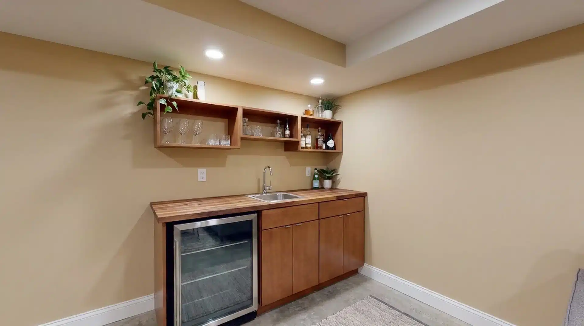 Small basement bar with compact counter, sink, open shelves, and under-counter refrigerator