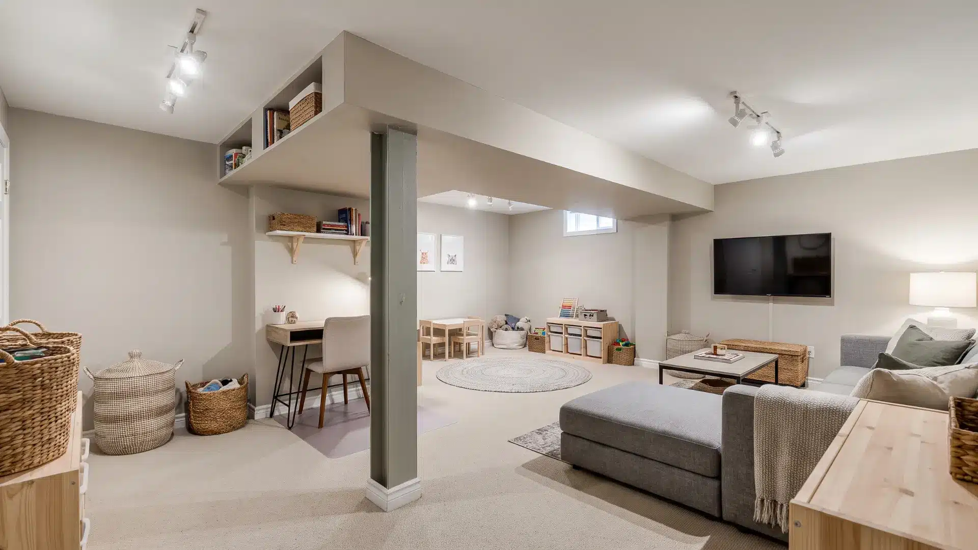 Small basement divided into flexible activity zones around a support column and low bulkhead.