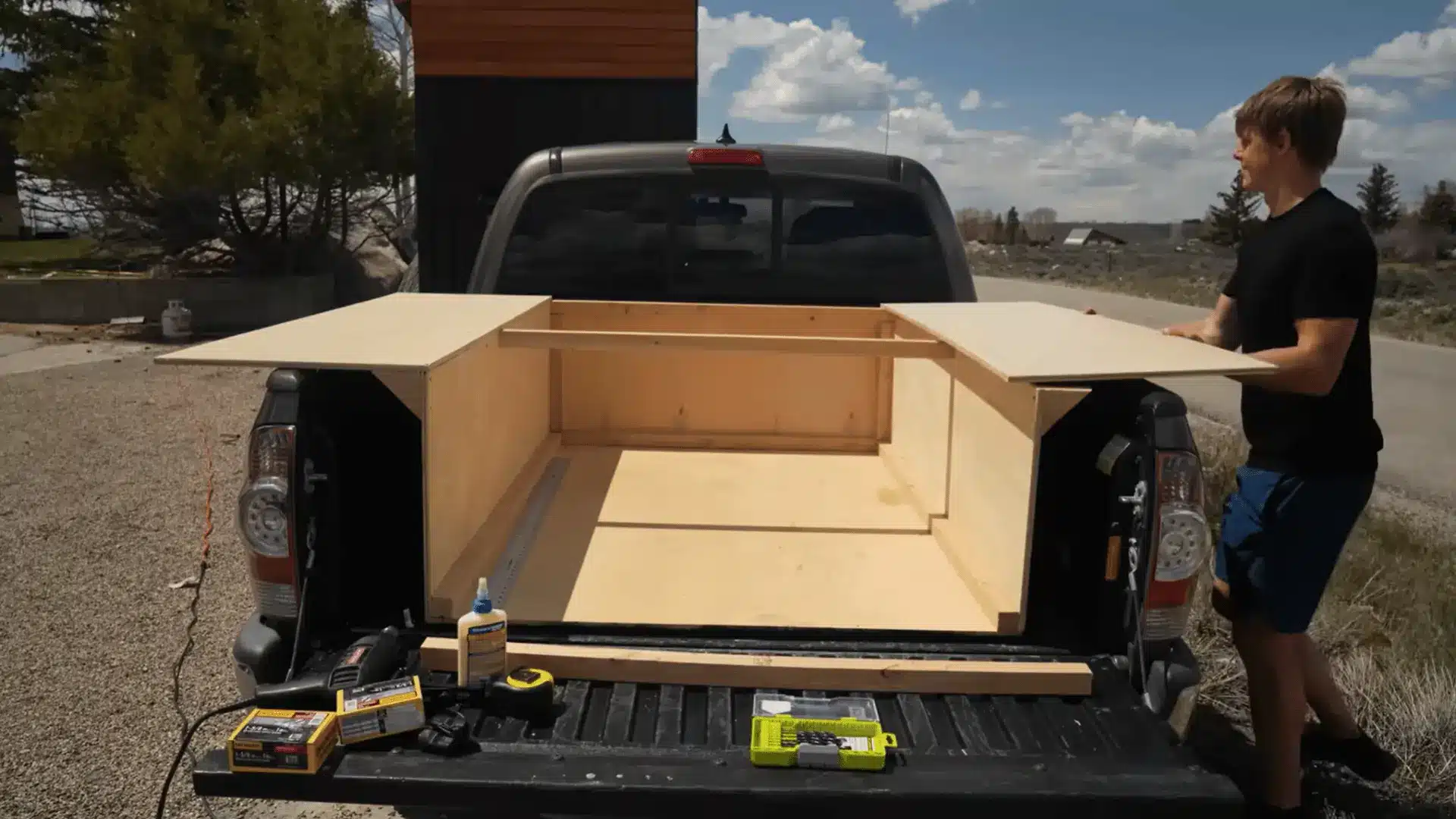 Plywood camper base installed in truck bed with extended side wings during early frame construction.