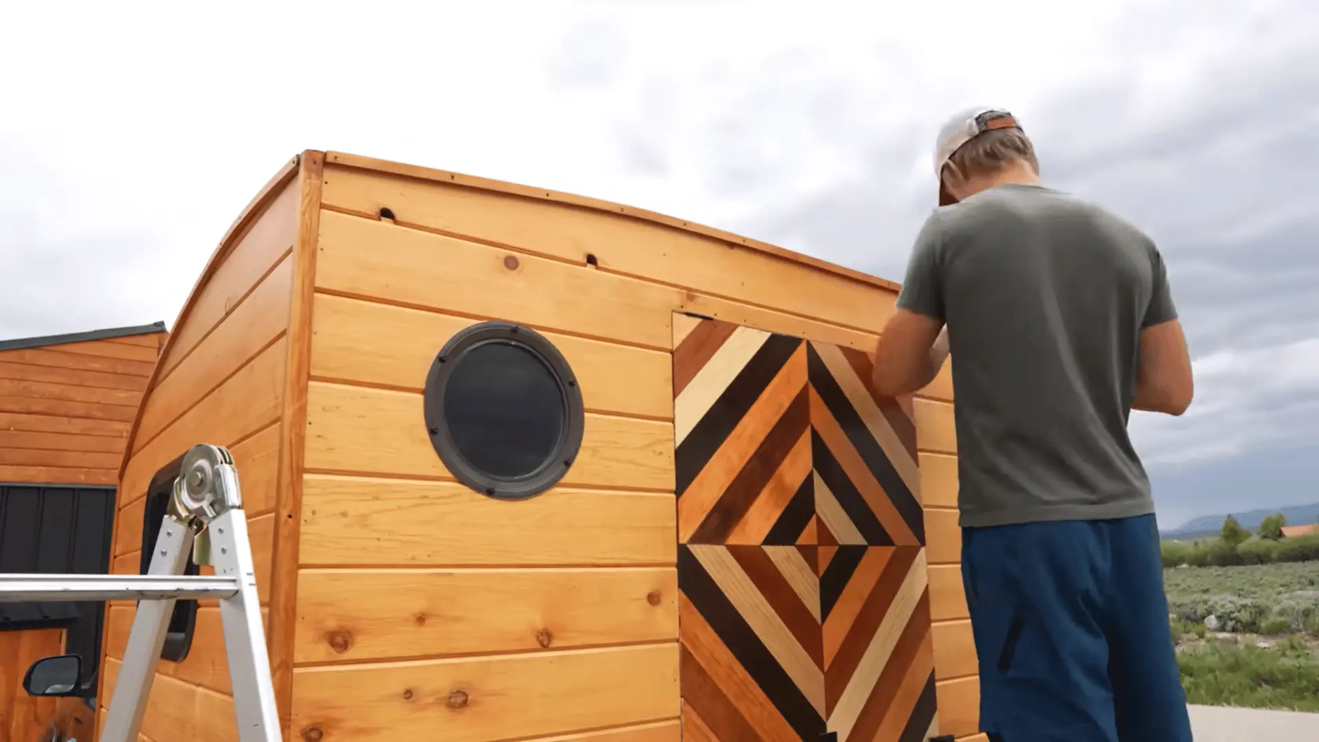 Wooden truck camper exterior with round window and decorative door trim installed.