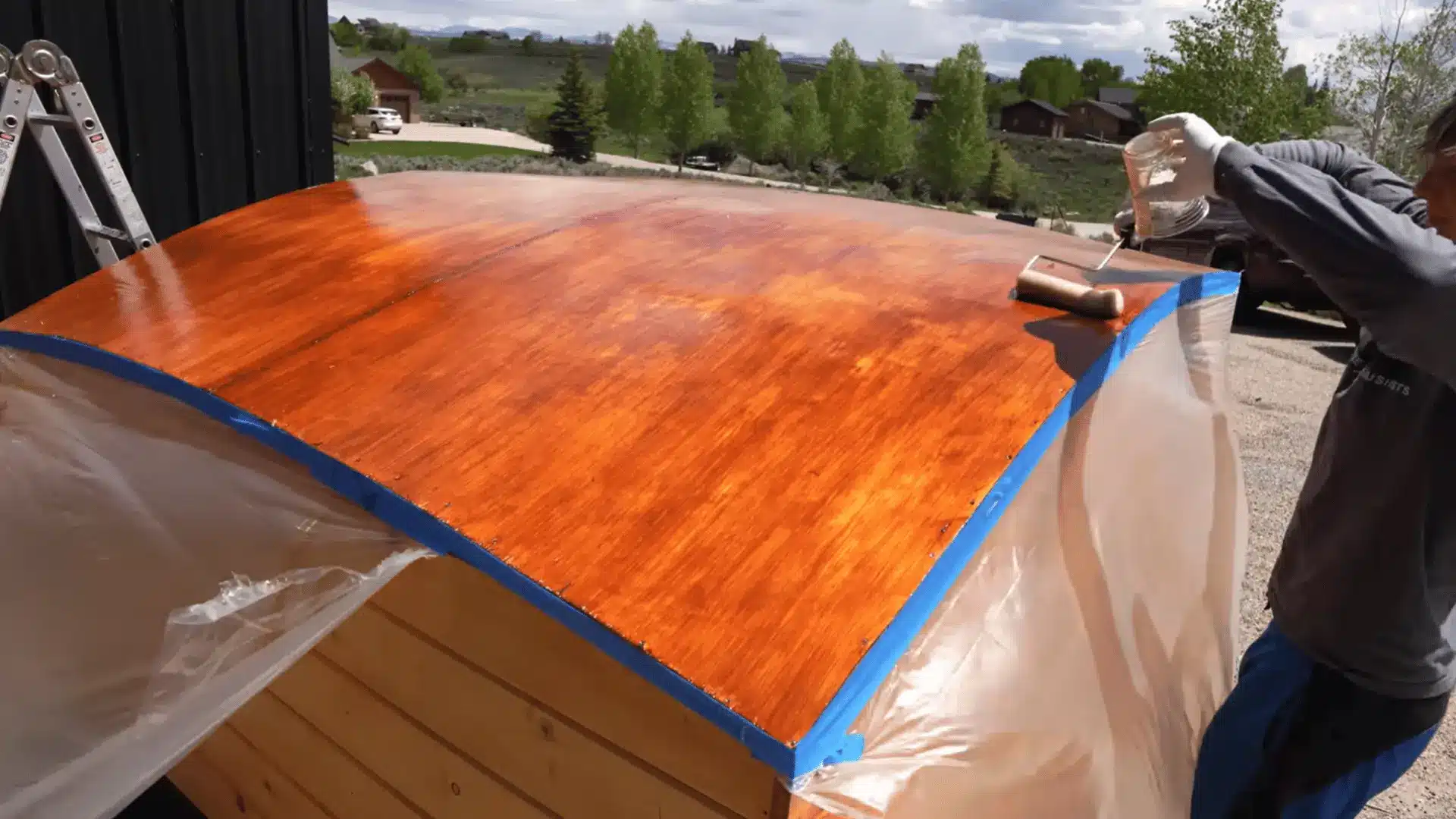 Wooden truck camper roof being stained before applying a protective fiberglass coating.