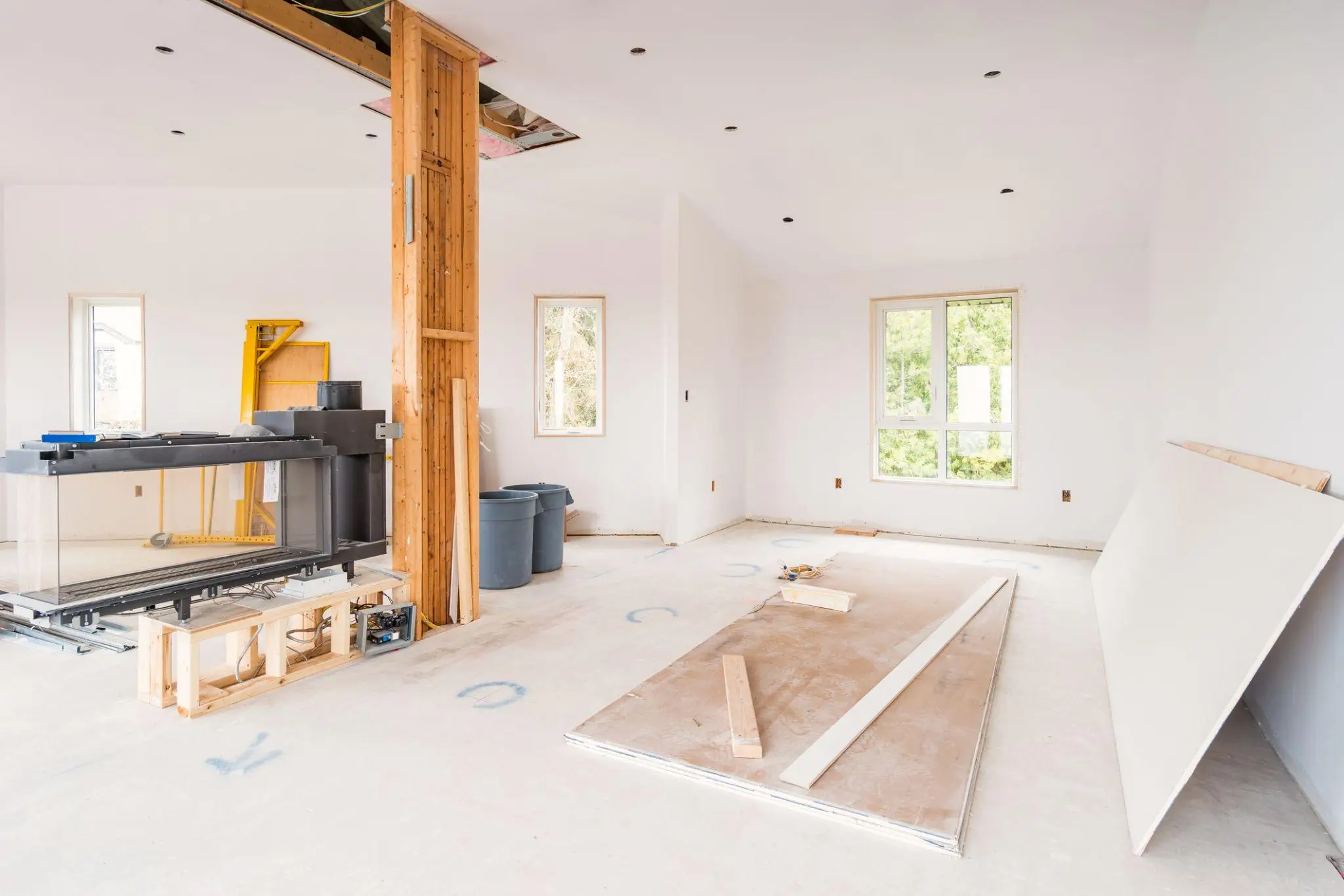 Renovation process in progress with unpainted walls, construction tools, and wooden support beams