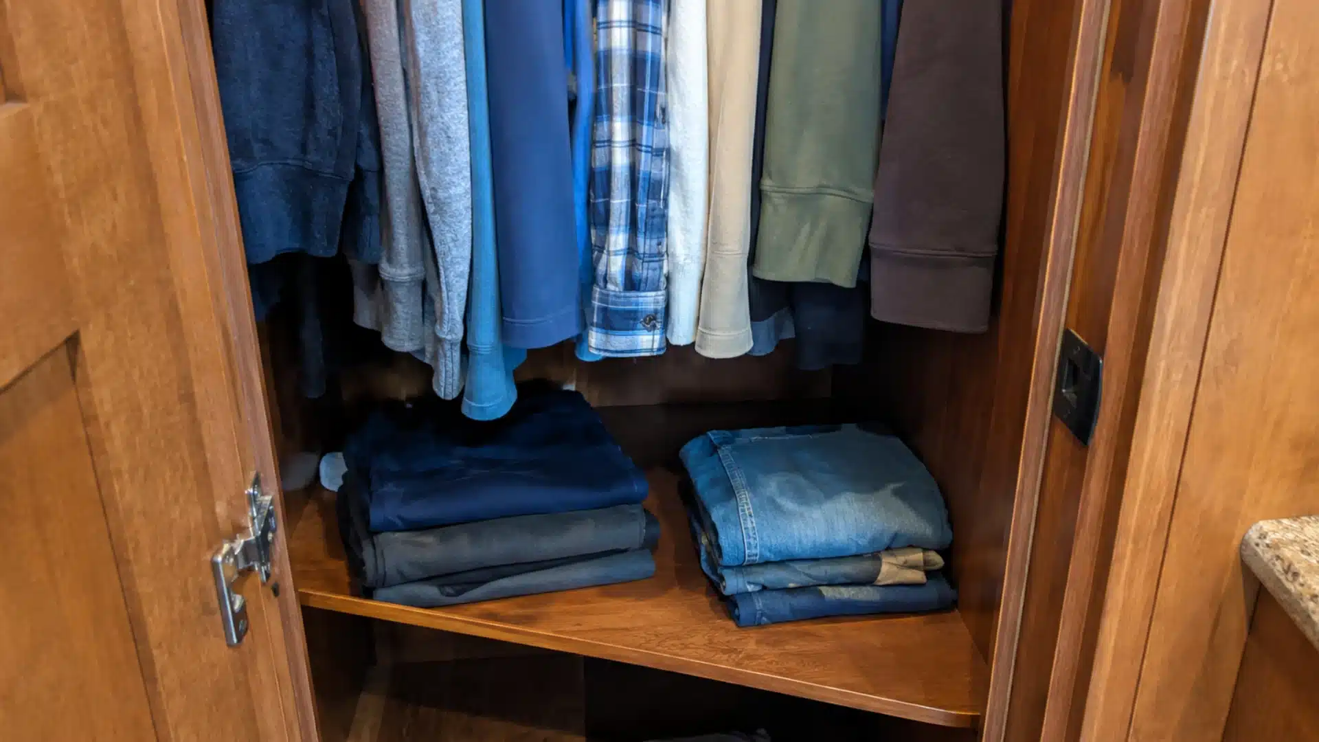 Wooden half-shelf installed inside an rv wardrobe under hanging clothes