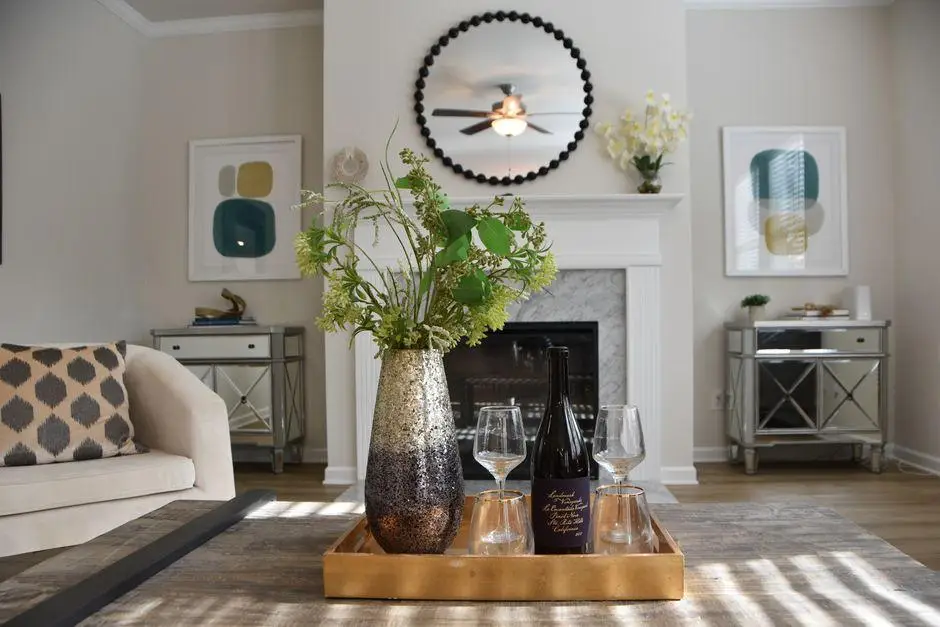 Vase with green foliage and wine bottle on tray in elegant living room