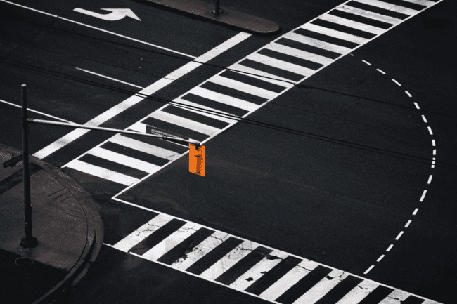Urban intersection with bold crosswalk lines and traffic light on empty street