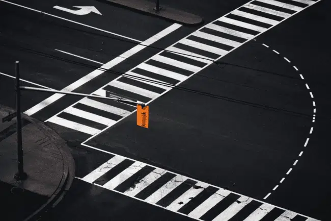 Urban intersection with bold crosswalk lines and traffic light on empty street