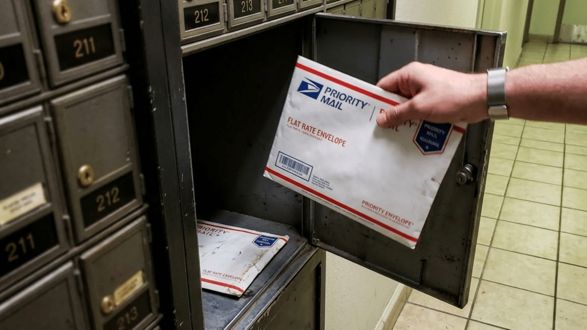 hand placing a usps priority mail flat rate envelope into an open po box locker with more mail inside