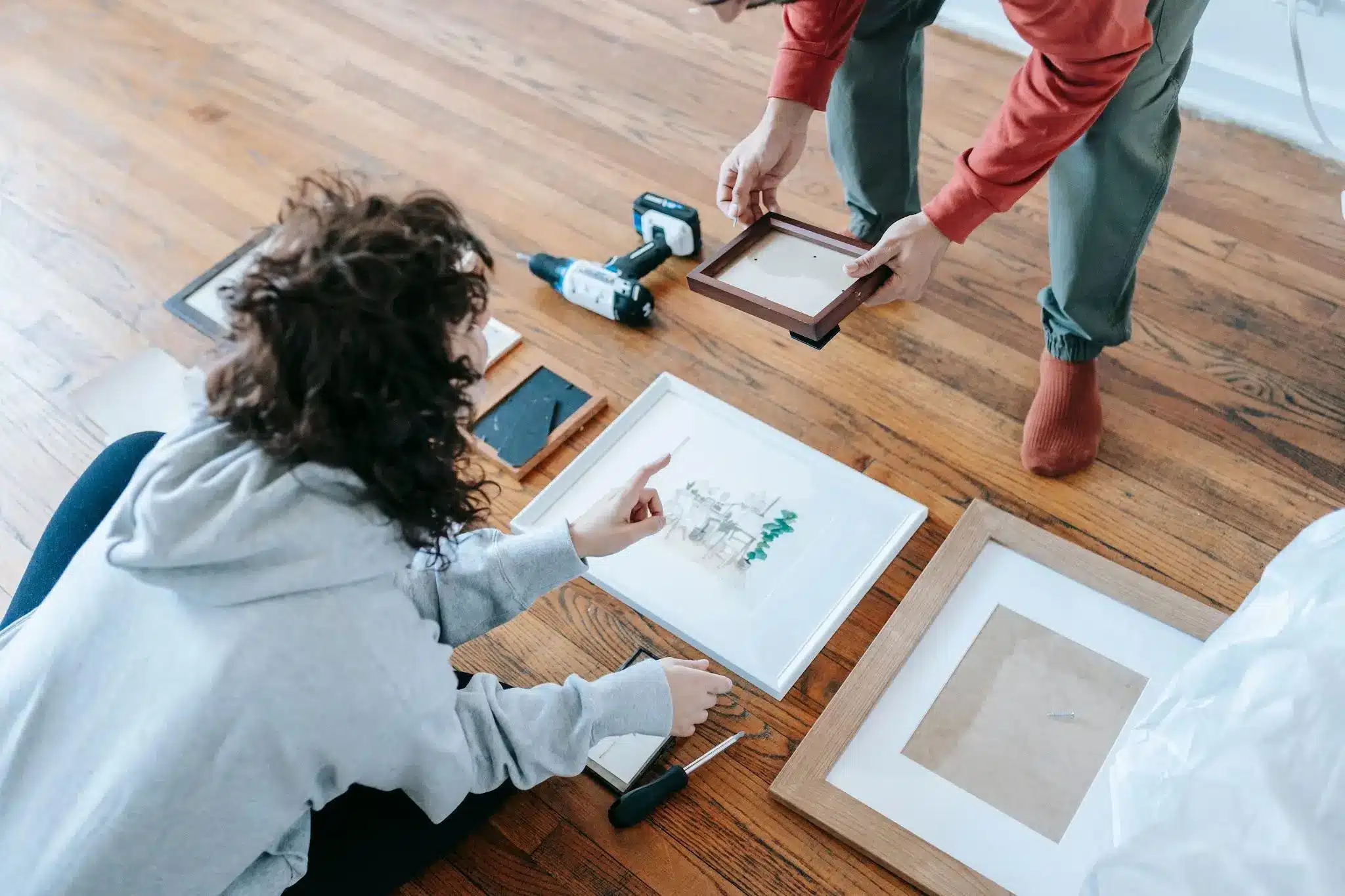 Framing artwork on wooden floor with tools and picture frames in cozy room