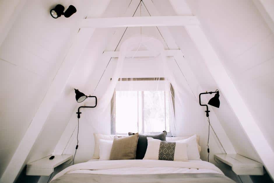 Cozy A-frame bedroom with white bed linens and soft pillows under natural light