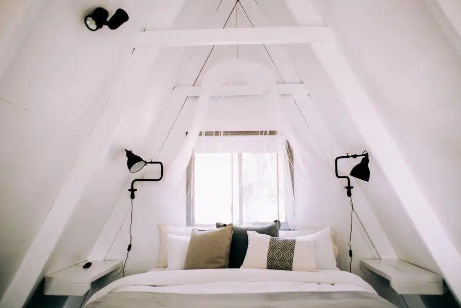 Cozy A-frame bedroom with white bed linens and soft pillows under natural light