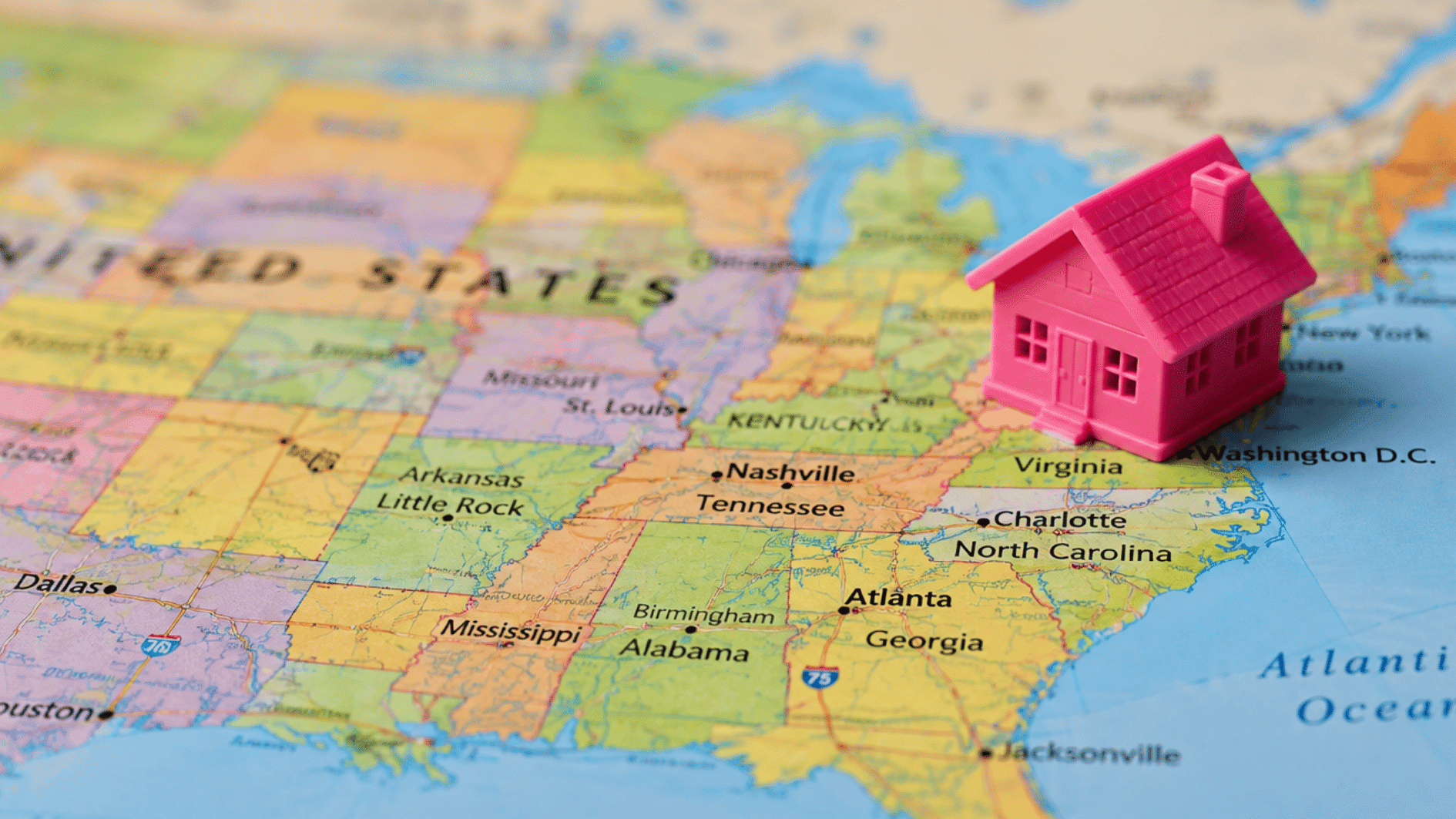 pink house model placed on a united states map to represent moving to another state across the country