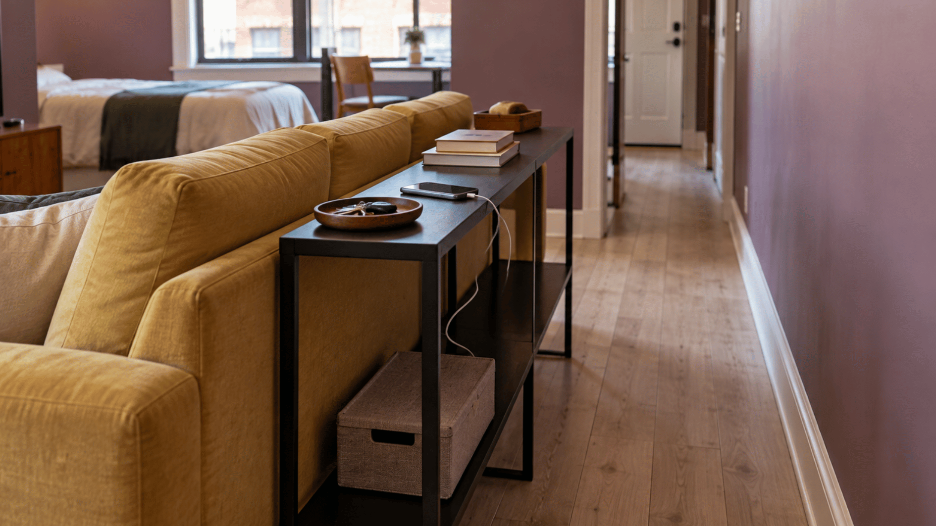 slim console behind a mustard sofa adds surface space while keeping the studio walkway clear