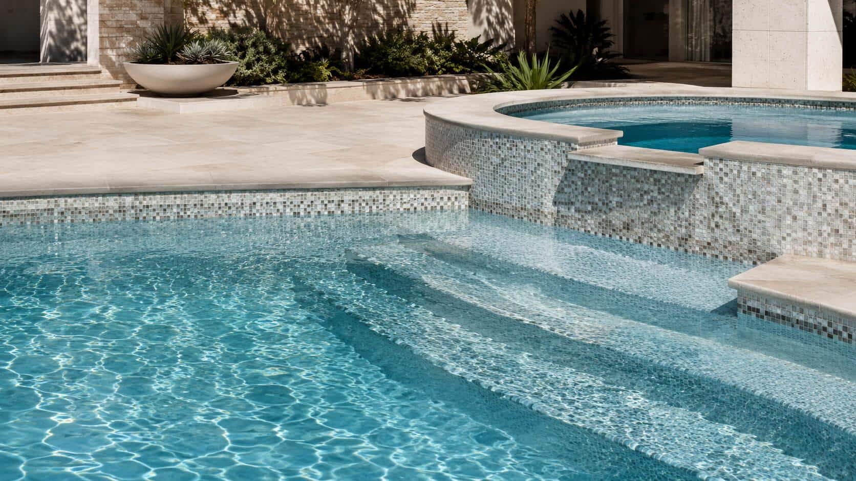 Outdoor swimming pool with clear water and tile design beside modern stone patio