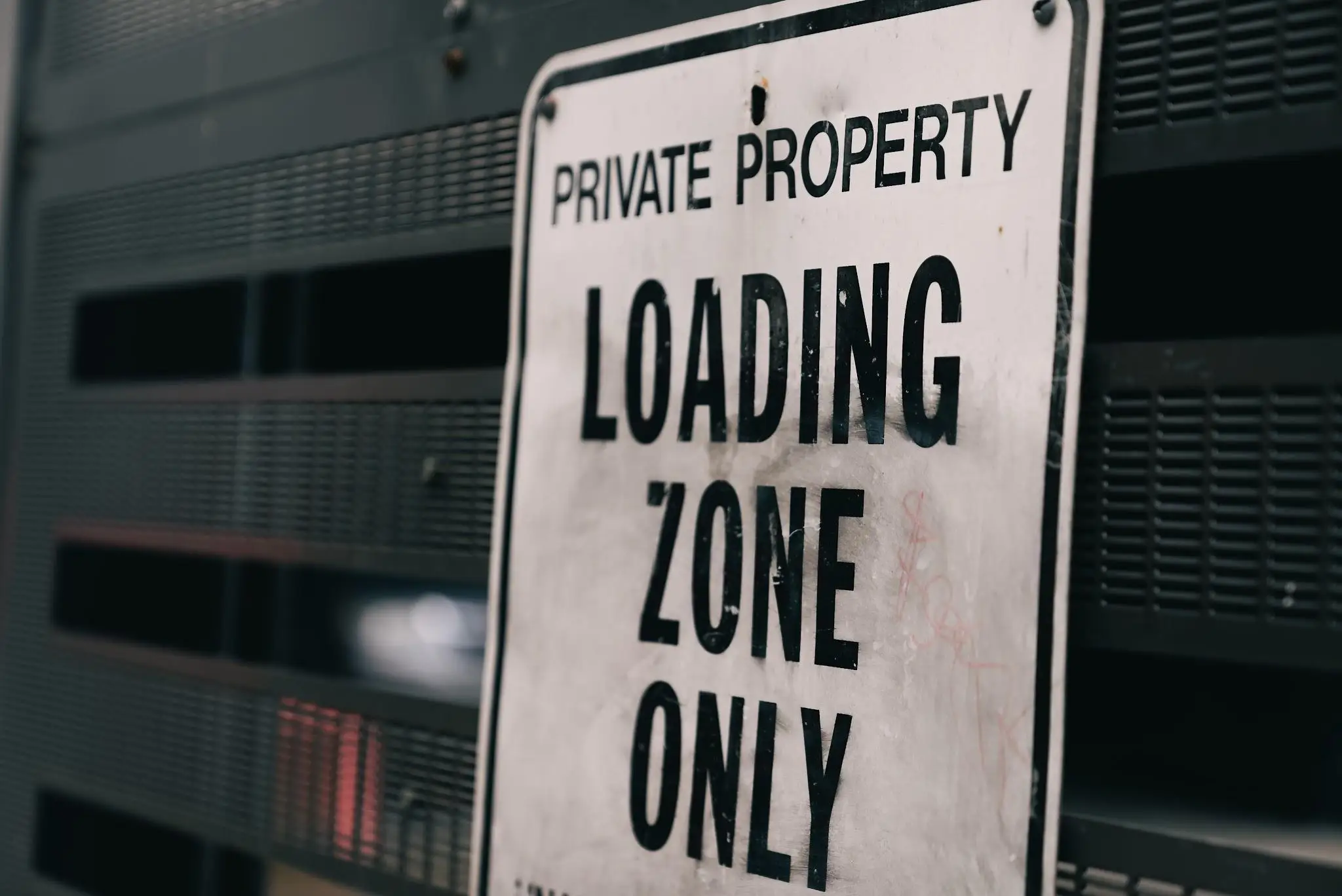 Private property loading zone sign mounted on dark perforated metal surface