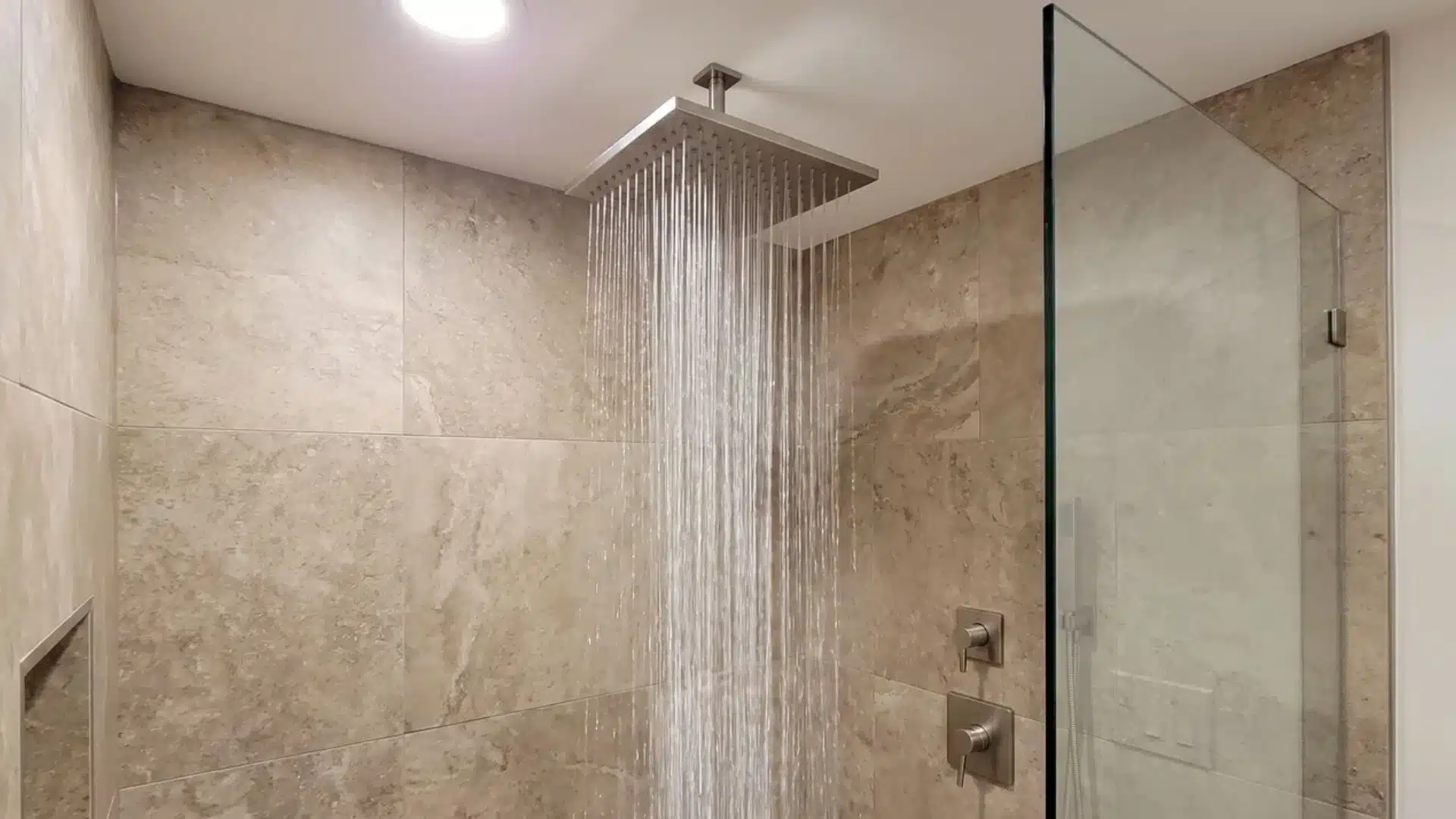 Rainfall showerhead creating a wide, gentle stream in a realistic spa bathroom.