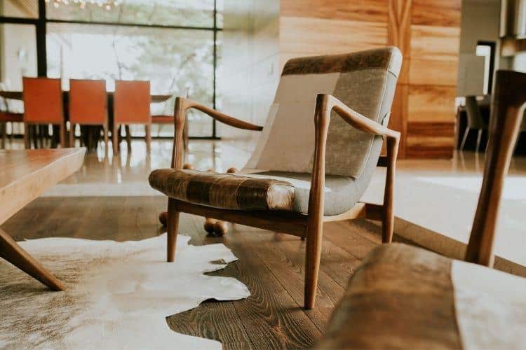 Mid-century modern armchair on wooden floor in sunlit living room with cowhide rug