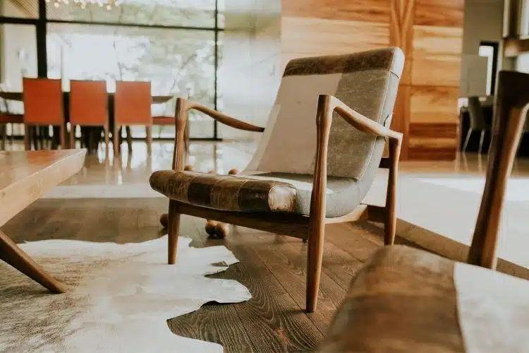Mid-century modern armchair on wooden floor in sunlit living room with cowhide rug
