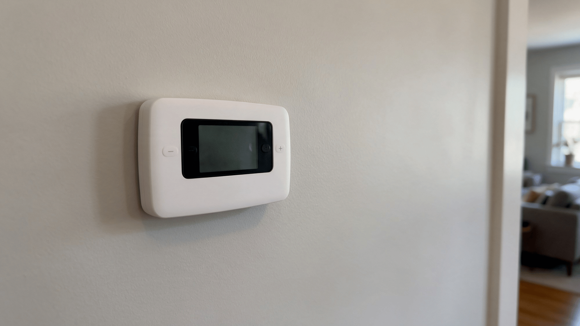 white wall-mounted thermostat with a blank black display screen