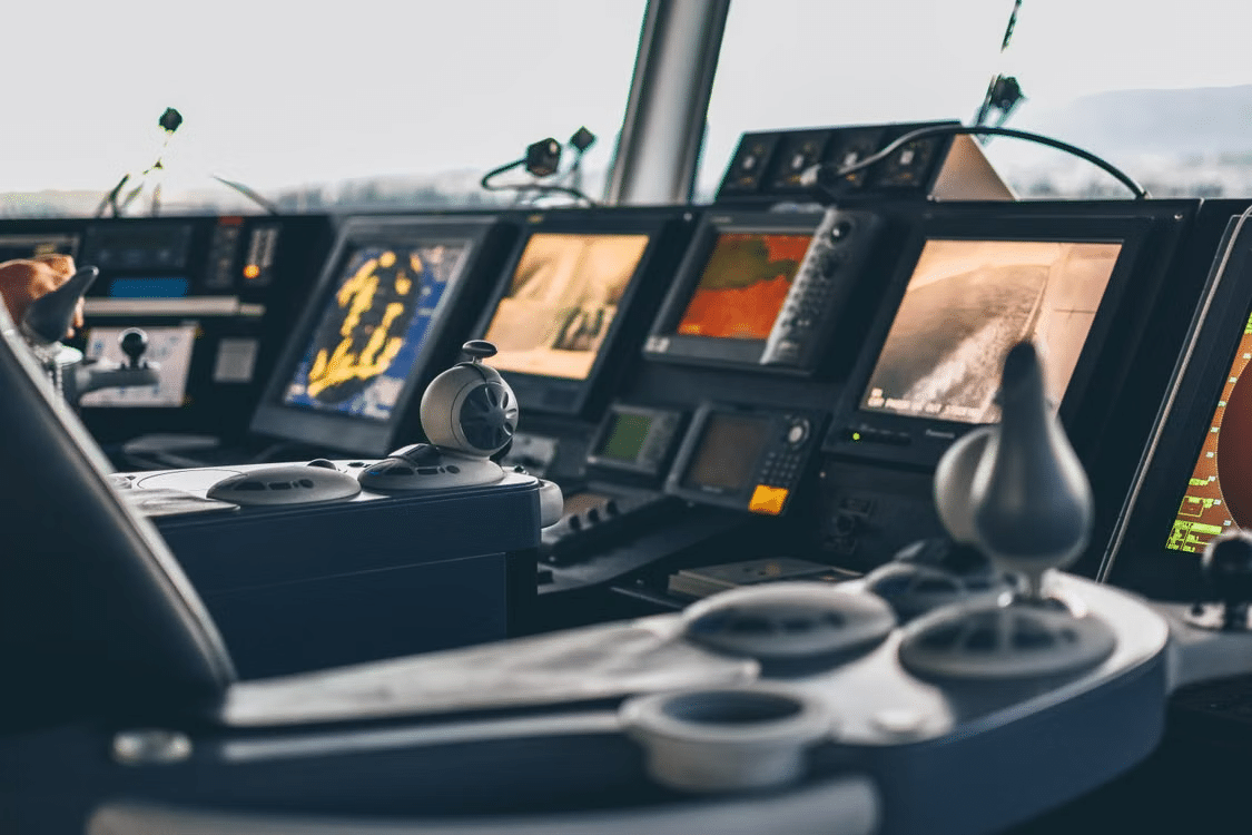 Control panel with multiple displays and controls in a ship cockpit under daylight
